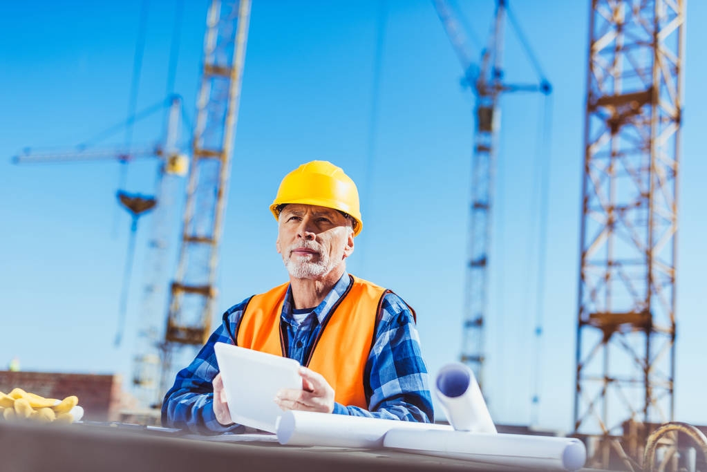 Construction worker on site with cranes in background